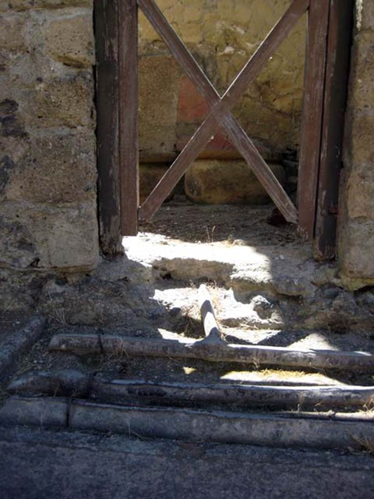 V.9 Herculaneum, June 2011. Looking east to doorway, across line of lead pipes in pavement.
Photo courtesy of Sera Baker.
